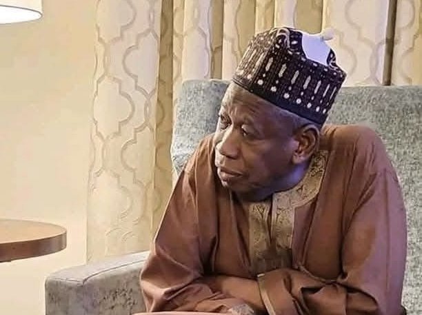 Former-APC-national-chairman-Abdullahi-Ganduje Abdullahi Ganduje seated indoors in traditional attire, looking contemplative.