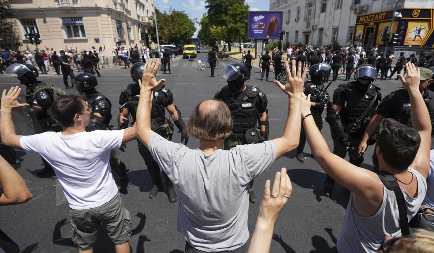 Serbia Cracks Down on Protests as Police Clear Barricades and Arrest Demonstrators Protesters in Serbia block a road in Belgrade, holding signs and chanting anti-government slogans as police stand nearby.