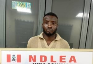 NDLEA officer displays a suspect arrested for drug trafficking at Murtala Muhammed International Airport.