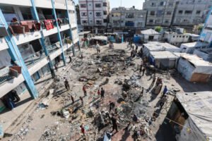 Aerial view of a destroyed neighborhood in Palestine with collapsed buildings and scattered debris.