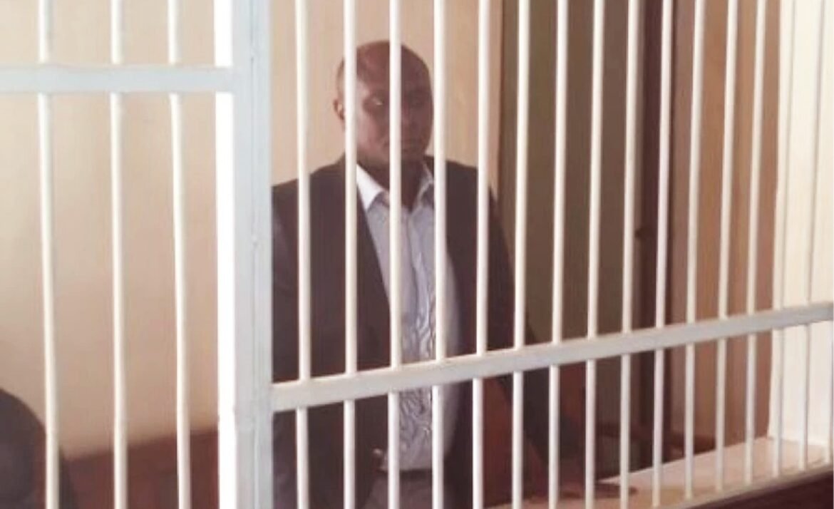 Man in formal attire stands behind courtroom bars after being charged with money laundering.