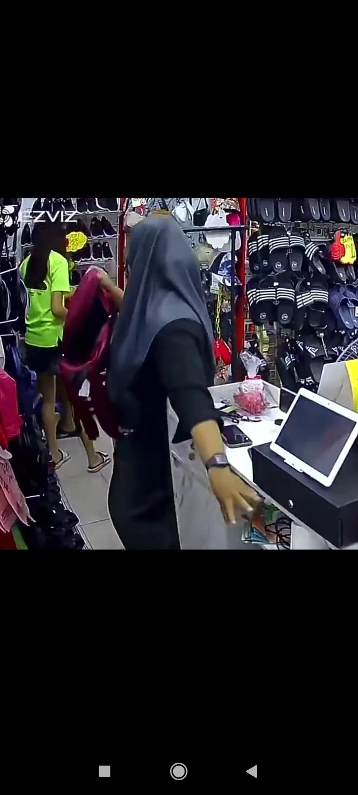 CCTV CCTV footage showing a thief disguised as a customer stealing money from under a shop counter in seconds.