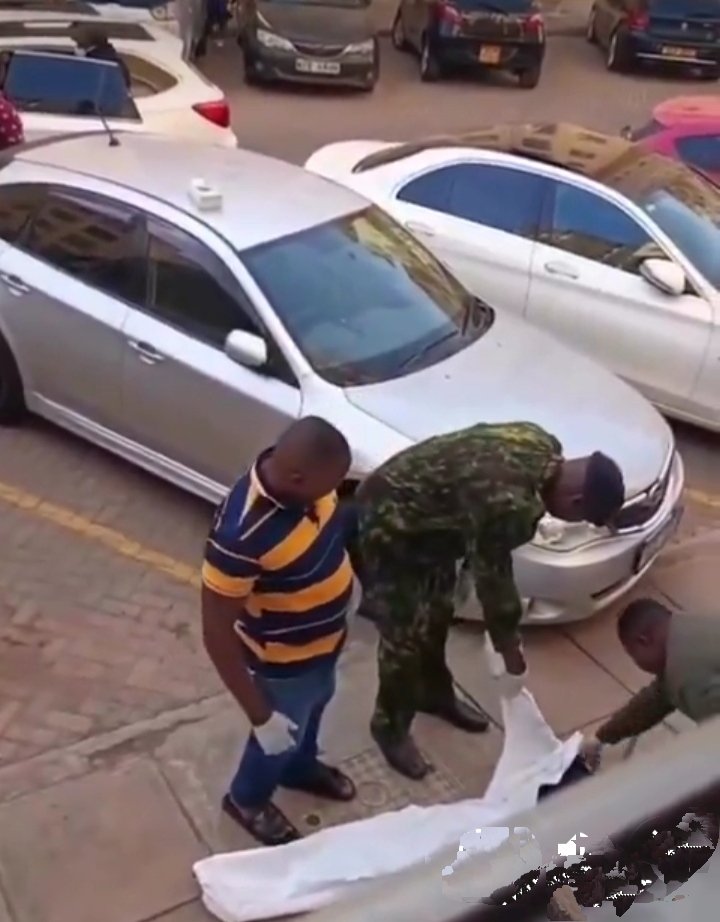 A crowd gathers around a tragic scene after a man falls from a 12-storey building, with police arriving to begin investigation.