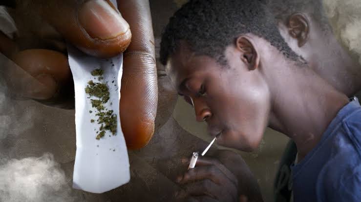 A crowd gathers around as a young man lies on the ground after collapsing from a suspected overdose of a drug called Colos.